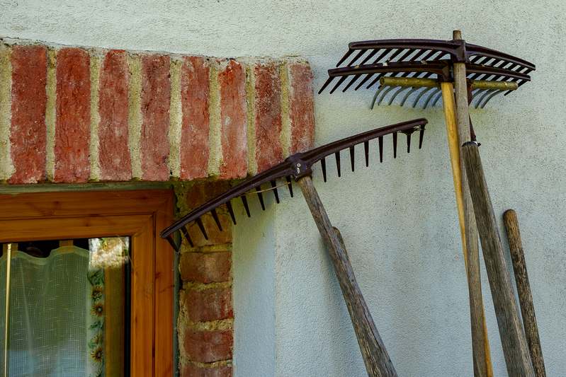 Close-up of hands holding a metal garden rake in soil